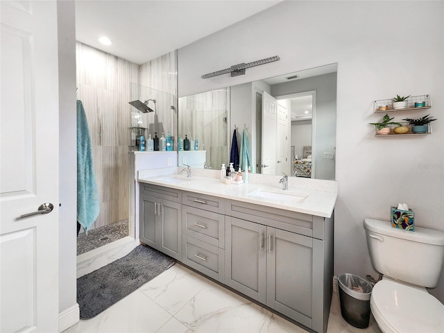 bathroom featuring vanity, a tile shower, and toilet