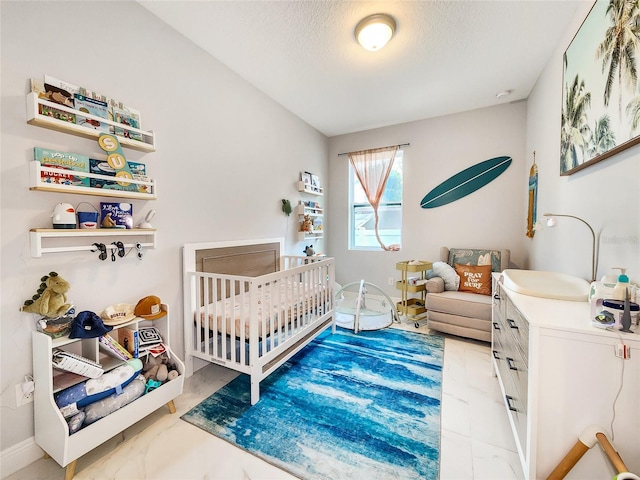 bedroom featuring a nursery area and a textured ceiling