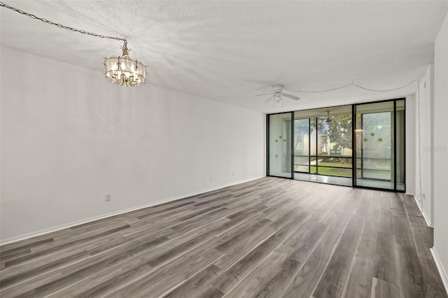 empty room with hardwood / wood-style flooring, a textured ceiling, expansive windows, and ceiling fan with notable chandelier