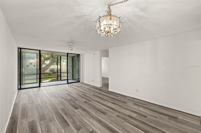 unfurnished living room with a textured ceiling, hardwood / wood-style flooring, ceiling fan with notable chandelier, and floor to ceiling windows