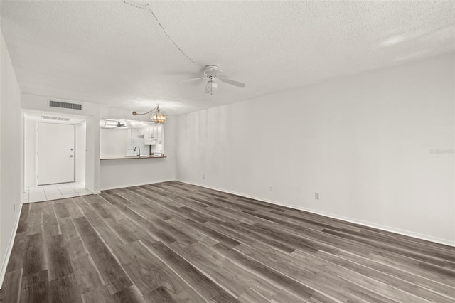 unfurnished living room featuring sink, dark wood-type flooring, a textured ceiling, and ceiling fan