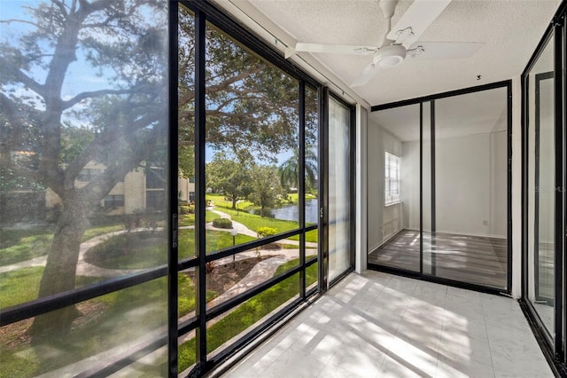 unfurnished sunroom with a water view and ceiling fan