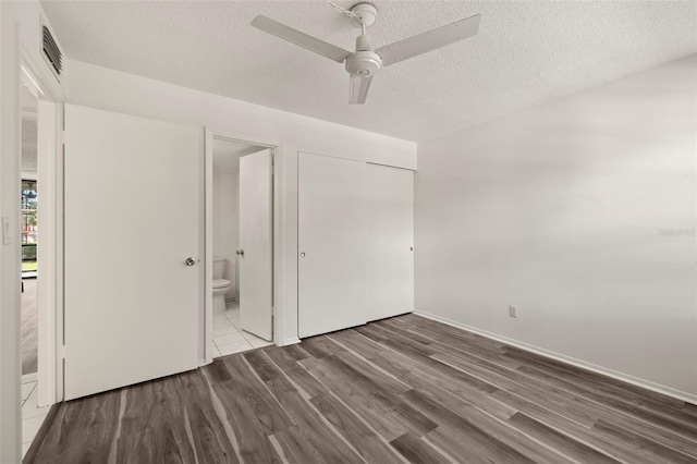 unfurnished bedroom featuring a closet, wood-type flooring, ensuite bathroom, a textured ceiling, and ceiling fan