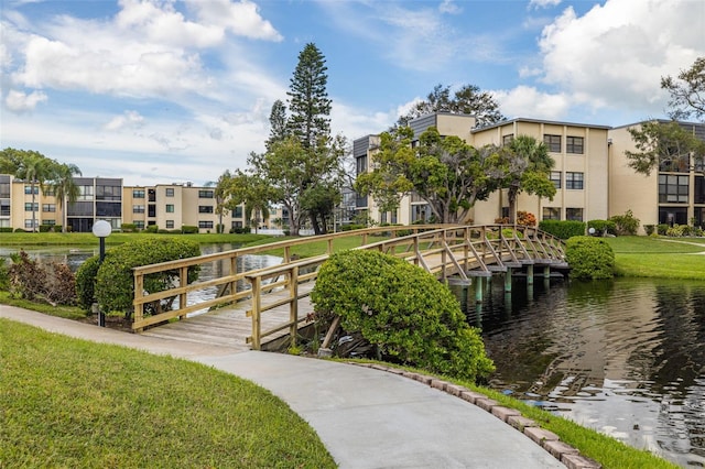 surrounding community with a water view and a lawn