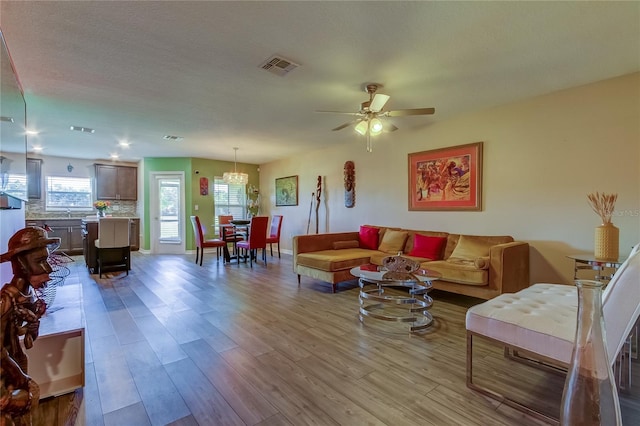 living room with light wood-type flooring, a textured ceiling, and ceiling fan