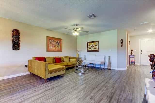 living room featuring light hardwood / wood-style floors, ceiling fan, and a textured ceiling