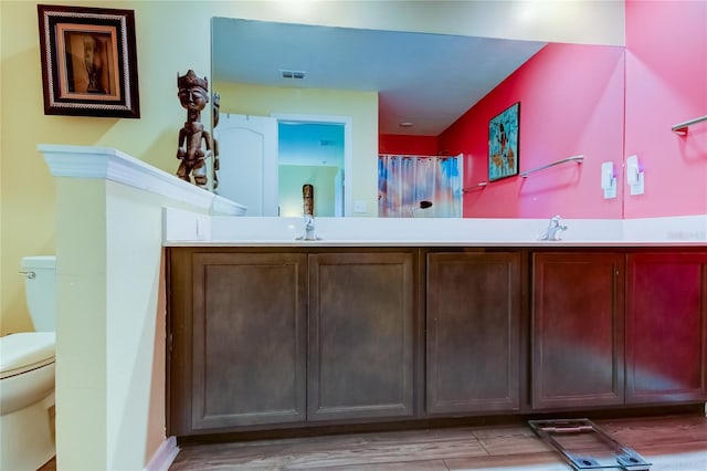 bathroom featuring wood-type flooring, vanity, and toilet