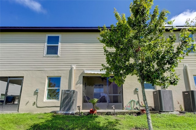 rear view of property featuring a lawn, cooling unit, and a sunroom