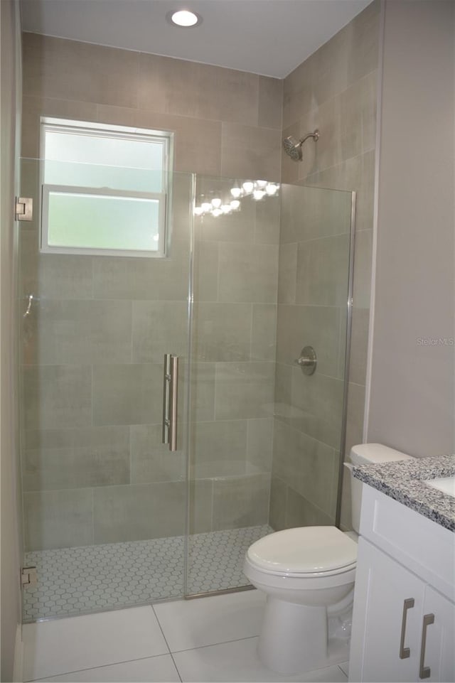 bathroom with vanity, a shower with shower door, toilet, and tile patterned floors