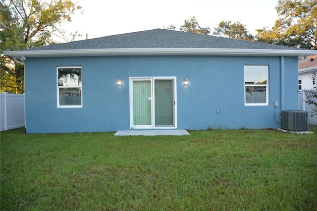 back of property with a yard and central AC