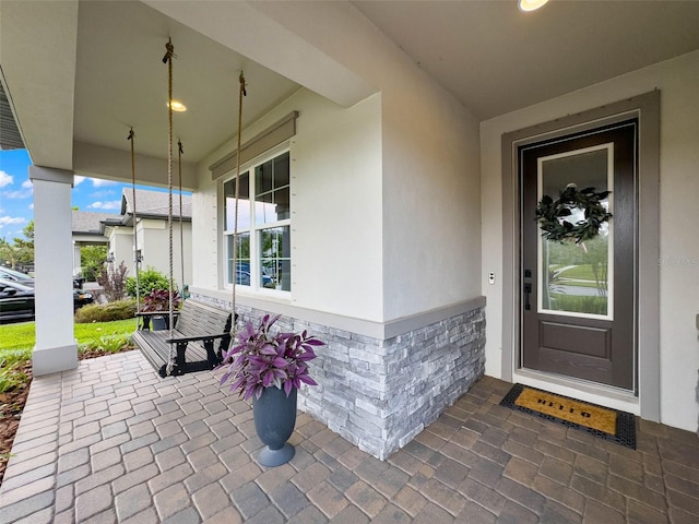 doorway to property featuring stucco siding and covered porch