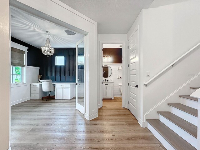 interior space with stairway, visible vents, light wood-type flooring, and a chandelier