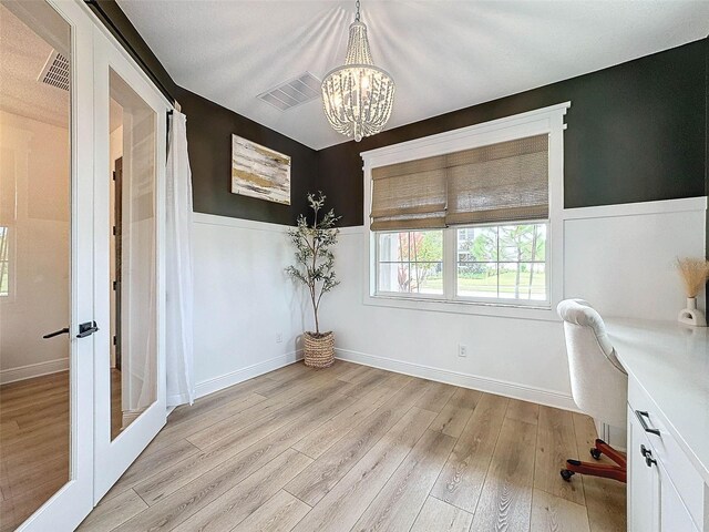 unfurnished office featuring light wood-type flooring, french doors, visible vents, and wainscoting