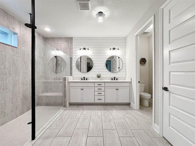 full bath featuring toilet, visible vents, a stall shower, and a sink