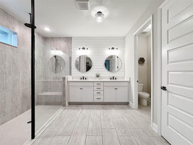bathroom with visible vents, a sink, toilet, and a shower stall