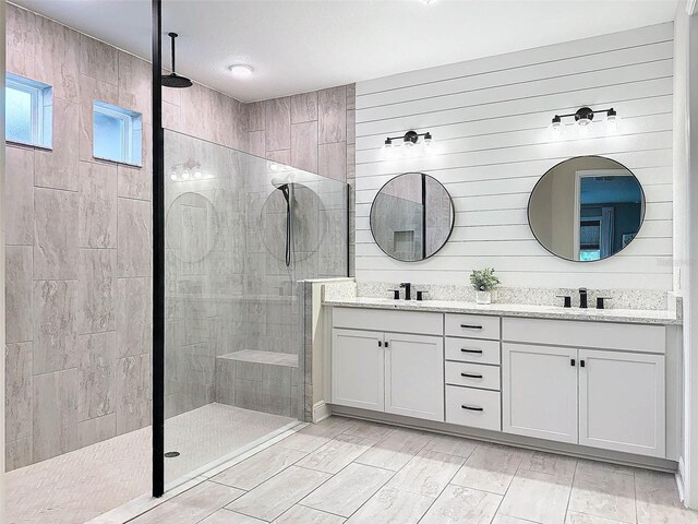 bathroom featuring double vanity, a walk in shower, and a sink