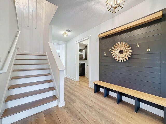 stairs with visible vents, a textured ceiling, baseboards, and wood finished floors