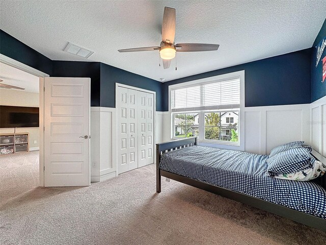 bedroom featuring visible vents, carpet, a closet, and wainscoting