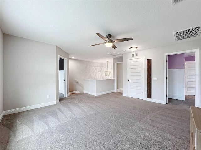 unfurnished living room with carpet flooring, a textured ceiling, ceiling fan, and visible vents