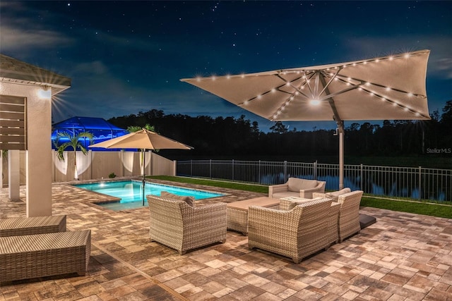 pool at night featuring a fenced backyard, an outdoor living space, a patio area, and a fenced in pool