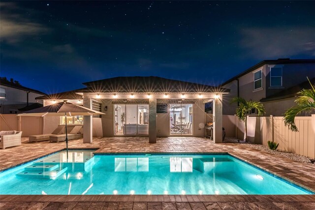 pool at twilight with a patio area, a fenced in pool, an outdoor structure, and fence