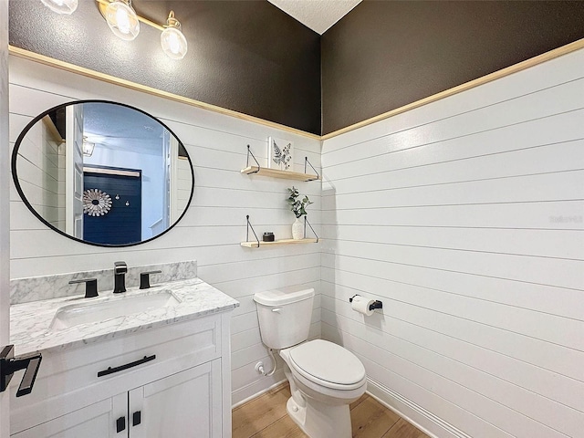 bathroom featuring toilet, wood finished floors, and vanity