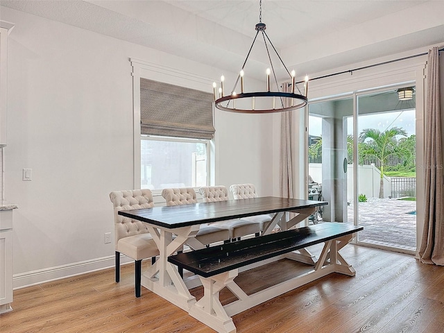 dining space featuring light wood-style flooring, an inviting chandelier, and baseboards