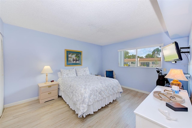 bedroom with light wood-type flooring and a textured ceiling