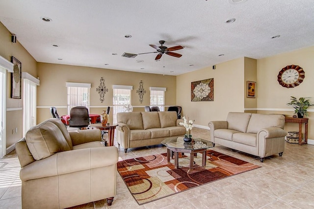 living room with ceiling fan, light tile patterned floors, and a textured ceiling