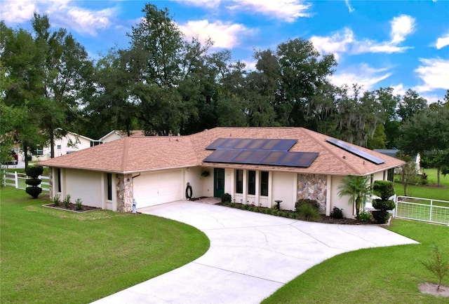 ranch-style home with a front yard, a garage, and solar panels