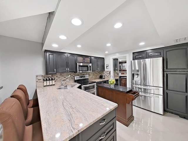 kitchen with sink, light stone countertops, tasteful backsplash, kitchen peninsula, and stainless steel appliances