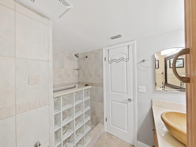 bathroom featuring a tile shower, vanity, and tile patterned floors