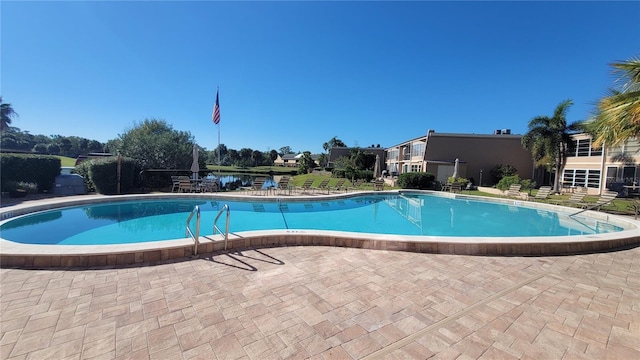 view of swimming pool featuring a water view and a patio