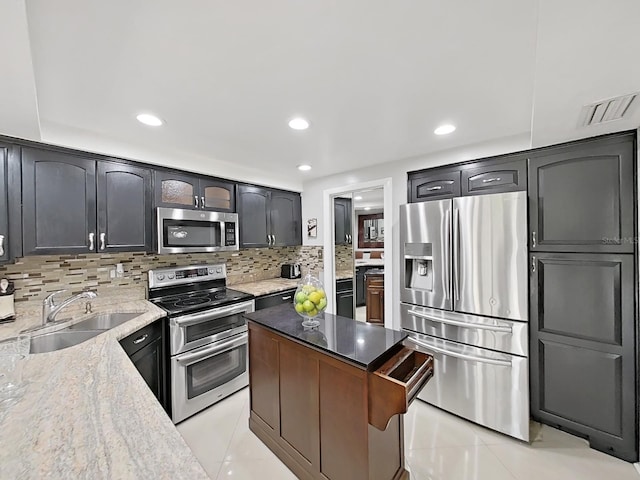 kitchen featuring light stone countertops, sink, decorative backsplash, light tile patterned flooring, and appliances with stainless steel finishes