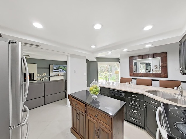 kitchen with sink, light stone countertops, stainless steel appliances, and light tile patterned floors