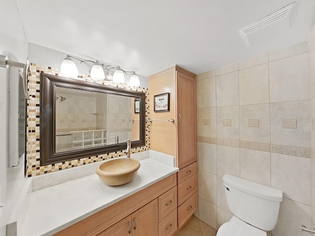 bathroom featuring vanity, toilet, tile walls, and backsplash