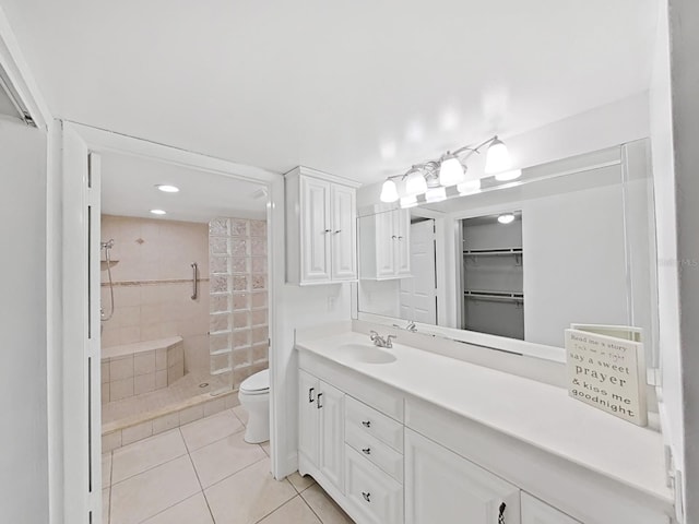 bathroom with tile patterned floors, toilet, a tile shower, and vanity