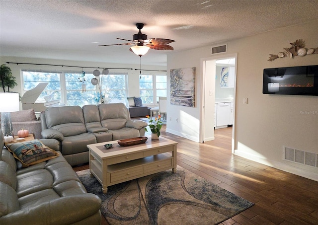 living room with wood-type flooring, a textured ceiling, a wealth of natural light, and ceiling fan