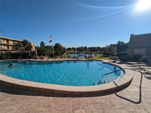 view of pool featuring a water view and a patio