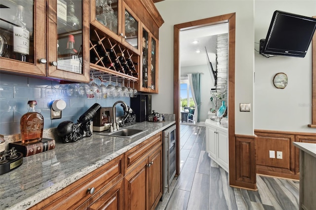 kitchen featuring light stone counters, sink, tasteful backsplash, beverage cooler, and light hardwood / wood-style flooring