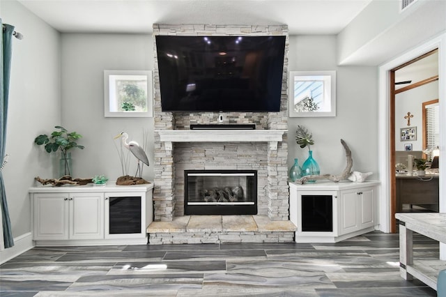 living room featuring plenty of natural light, dark wood-type flooring, and a stone fireplace