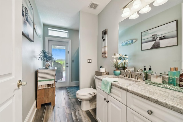 bathroom featuring toilet, vanity, and hardwood / wood-style floors