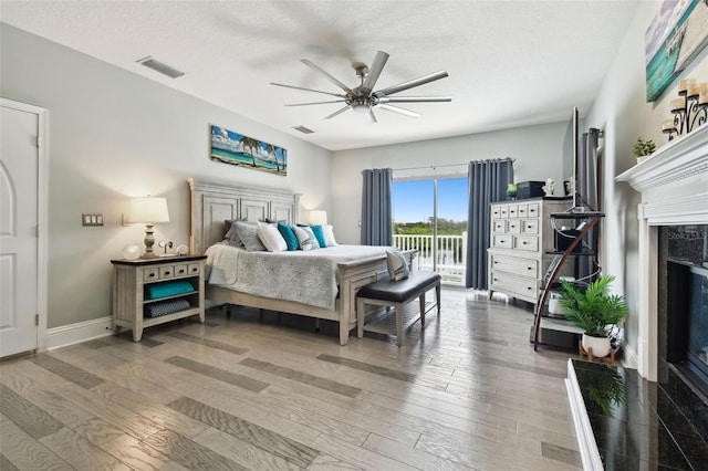 bedroom with access to outside, a fireplace, hardwood / wood-style floors, and ceiling fan