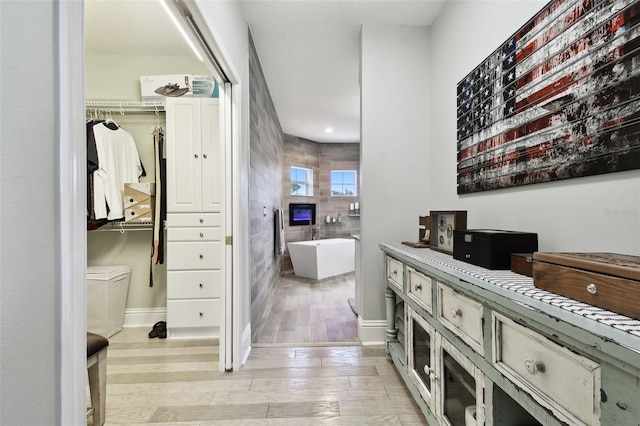 hallway featuring tile walls and light hardwood / wood-style floors