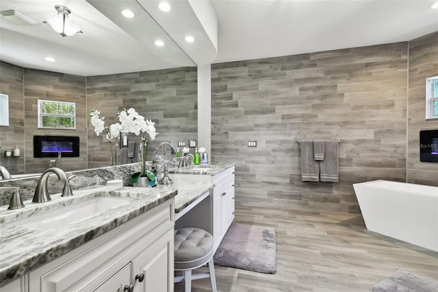 bathroom featuring tile walls, wood-type flooring, vanity, and a bathtub