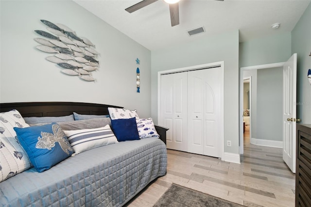 bedroom with light wood-type flooring, ceiling fan, and a closet