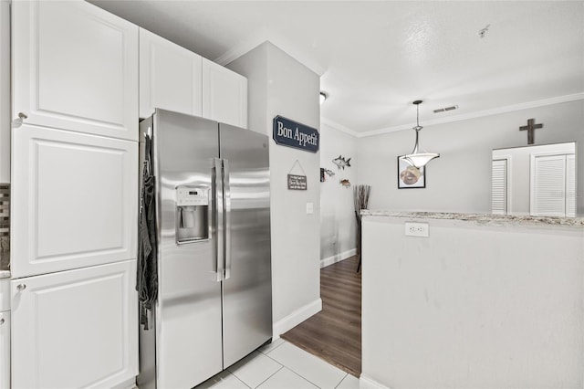 4221 W Spruce St Unit 1424, Tampa, FL 33607 - kitchen featuring stainless steel refrigerator with ice dispenser, crown molding, white cabinets, baseboards, and light tile patterned flooring