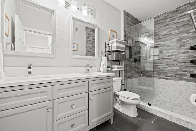 bathroom with tile patterned flooring, a shower with shower door, vanity, and toilet