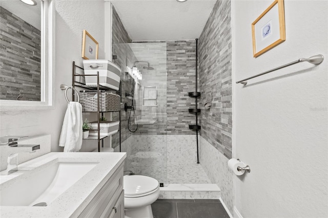 bathroom featuring vanity, a textured ceiling, a tile shower, tile patterned floors, and toilet