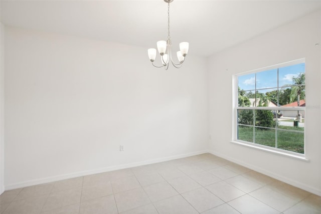 tiled spare room featuring a chandelier